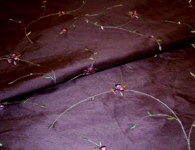 Closeup folded image of Silk Dupioni Kala color Aubergine with embroidery fabric from World Wide Fabrics, delicate`floral pattern